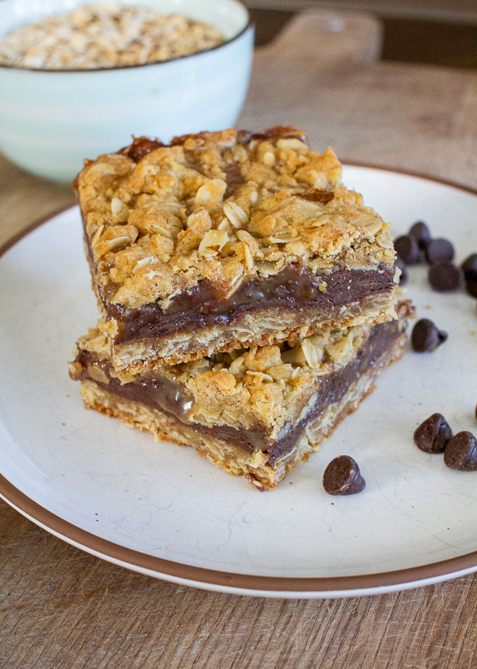 stack of easy caramel chocolate bars with a bowl of oats