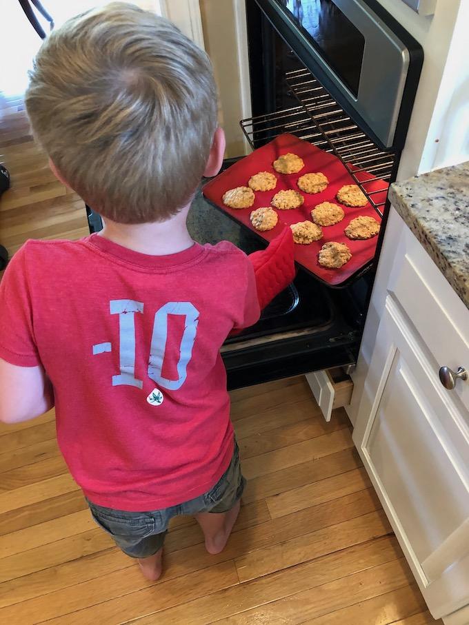 The Ultimate Guide to Teaching Kids To Cook 4 kid putting cookies in the oven
