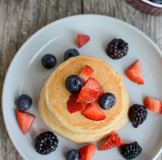 stack of fluffy whole wheat pancakes topped with fresh berries