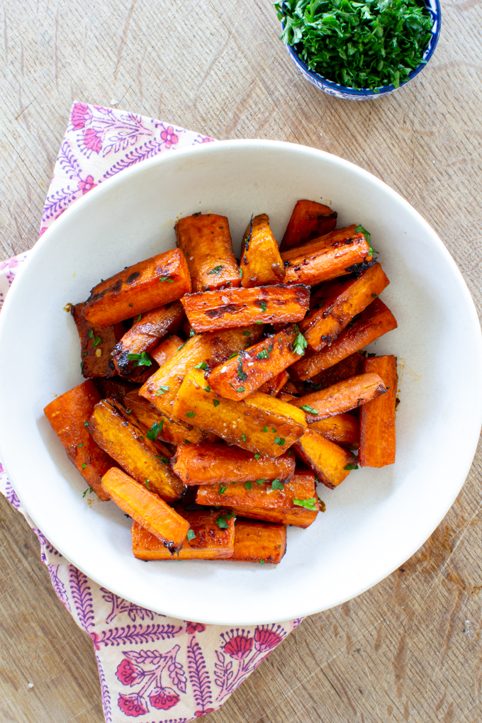 bowl of maple glazed carrots garnished with fresh herbs